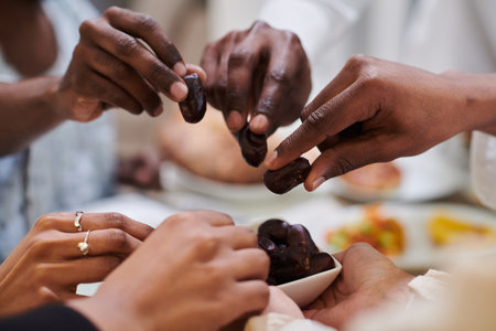 In a poignant close-up, the diverse hands of a Muslim family delicately grasp fresh dates, symbolizing the breaking of the fast during the holy month of Ramadan, capturing a moment of cultural unity, shared tradition, and the joyous anticipation of communal iftarの写真素材