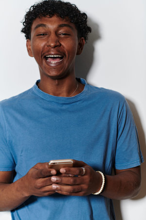 African American teenager engages with his smartphone against a pristine white background,...