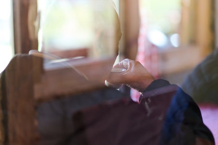 Captured through the soft lens of a window, an elderly man enjoys a quiet moment of reflection and solitude in the early morning, sipping his coffee and embracing the tranquil ambiance that accompanies the dawnの写真素材