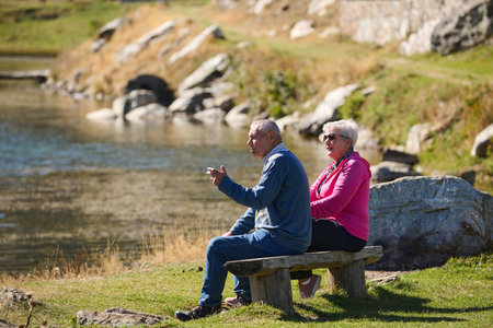 Elderly couple finding solace and joy as they rest on a park bench, engaged in heartfelt conversation, following a rejuvenating strol a testament to the enduring companionship and serene connection that accompanies the golden yearsの写真素材
