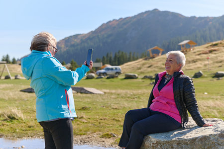 An elderly pair of women captures a timeless moment on their smartphones, blending technology with the serene beauty that surrounds themの写真素材