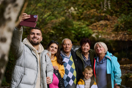 Radiant with joy, a happy family captures precious moments in nature as they share smiles and laughter while taking a selfie with a smartphone, creating cherished memories against the backdrop of the wholesome outdoorsの写真素材