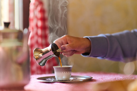 Elderly woman savors the serenity of the morning as she enjoys a cup of coffee on the porch of her rustic cottage, finding solace in the simplicity of nature and contemplative momentsの写真素材