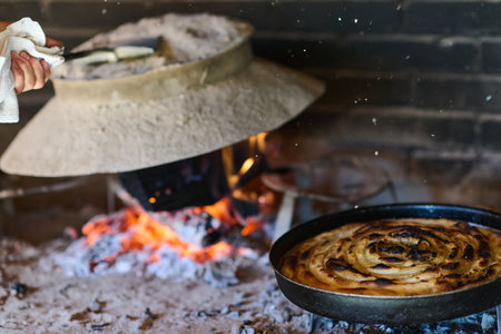 Capturing the essence of Bosnian culinary tradition, step-by-step preparation of a traditional Bosnian pie, showcasing the meticulous craftsmanship and authentic flavors involved in the culinary journeyの写真素材