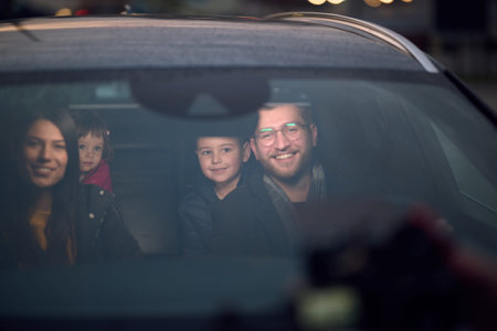 In the nighttime hours, a happy family enjoys playful moments together inside a car as they journey...