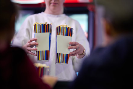 A vendor stands outside the cinema, holding freshly popped popcorn to sell to moviegoers before they enter the theaterの写真素材