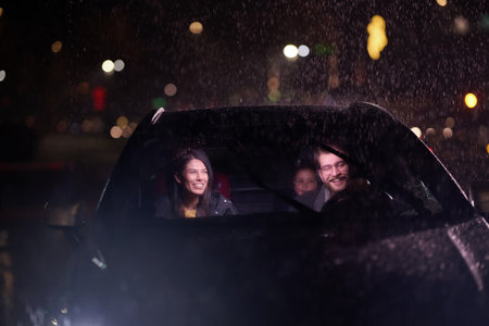 In the midst of a nighttime journey, a happy family enjoys playful moments inside a car as they travel through rainy weather, illuminated by the glow of headlights, laughter, and bondingの写真素材