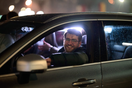 A modern businessman, donning eyeglasses, confidently drives his sleek car through the urban...