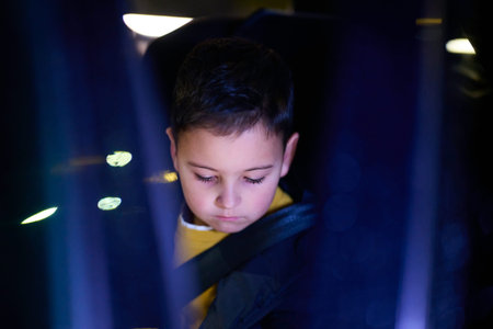 A young boy enjoys a car ride, captured through the window, as he observes the passing scenery.