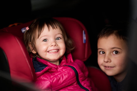 A young brother and sister enjoying a car ride together, immersed in the adventure of travel