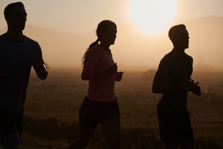 A group of friends, athletes, and joggers embrace the early morning hours as they run through the...