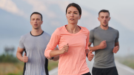 A group of friends, athletes, and joggers embrace the early morning hours as they run through the...
