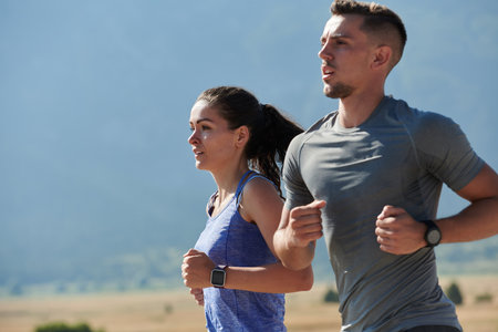 Energized by the beauty of nature, a couple powers through their morning run, their bodies and spirits invigorated.の写真素材