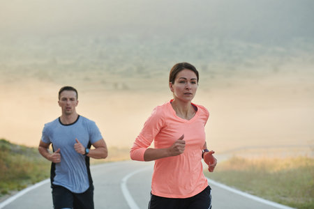 Energized by the beauty of nature, a couple powers through their morning run, their bodies and...