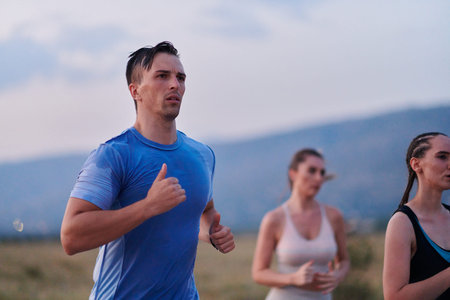 A diverse group of runners trains together at sunset.