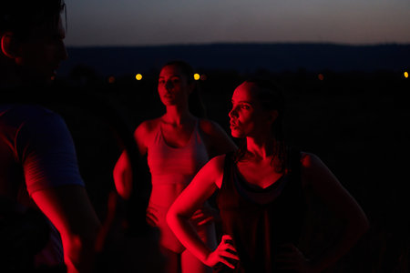Diverse Athletes Unwind: Post-Marathon Rest Under Red Nighttime Glow.の写真素材