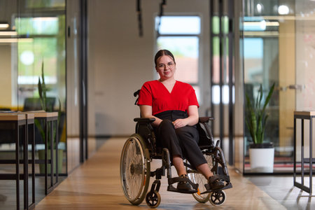 A modern young businesswoman in a wheelchair is surrounded by an inclusive workspace with...