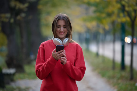 Sporty woman checks smartphone before doing some exercises listens music from a playlist