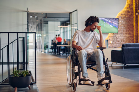 A sad businessman in a wheelchair occupies a hallway within a modern startup coworking center, embodying inclusivity and determination in the business environmentの写真素材