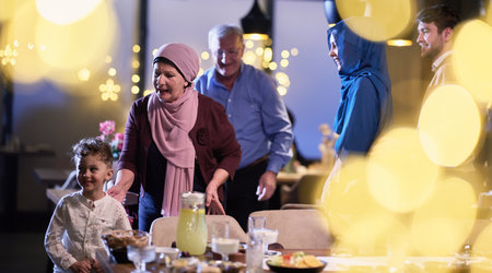 Grandparents arrive at their childrens and grandchildrens gathering for iftar in a restaurant during the holy month of Ramadan, bearing gifts and sharing cherished moments of love, unity, and cultural exchange, as they eagerly await their meal togetherの写真素材