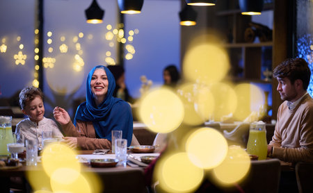 In a modern restaurant, an Islamic couple and their children joyfully await their iftar meal during the holy month of Ramadan, embodying familial harmony and cultural celebration amidst the contemporary dining ambianceの写真素材