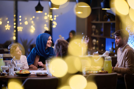 In a modern restaurant, an Islamic couple and their children joyfully await their iftar meal during the holy month of Ramadan, embodying familial harmony and cultural celebration amidst the contemporary dining ambianceの写真素材