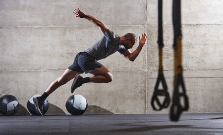 A muscular man captured in air as he jumps in a modern gym, showcasing his athleticism, power, and determination through a highintensity fitness routineの写真素材