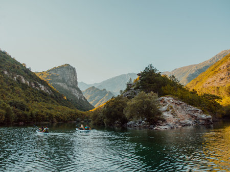A group of friends enjoying having fun and kayaking while exploring the calm river, surrounding forest and large natural river canyonsの写真素材