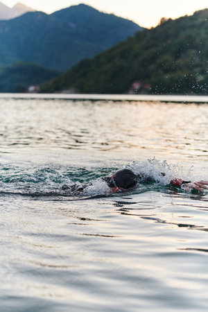 A professional triathlete trains with unwavering dedication for an upcoming competition at a lake, emanating a sense of athleticism and profound commitment to excellence.の写真素材