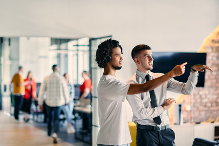 A group of colleagues, including an African American businessman and a young leader in a shirt and tie, pose together in a modern coworking center office, representing a dynamic blend of professionalism and collaborationの写真素材
