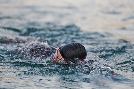 A professional triathlete trains with unwavering dedication for an upcoming competition at a lake,...