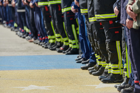 A group of firefighters lined up, saluting the flag, applauding in solidarity, and gearing up for intensive training sessions, showcasing their unwavering commitment to service and teamwork.の写真素材