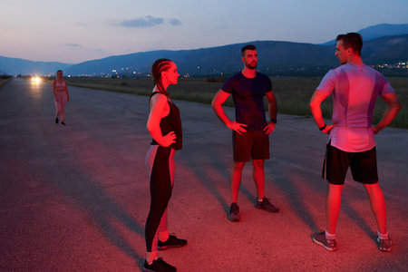 Diverse Athletes Unwind: Post-Marathon Rest Under Red Nighttime Glow.の写真素材