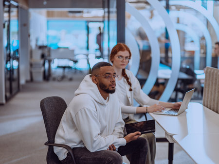 In a modern office setting, an African American businessman and his Muslim colleague, wearing a...