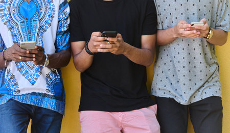 Diverse Teen Group Standing Together Against Wall Using Smartphones
