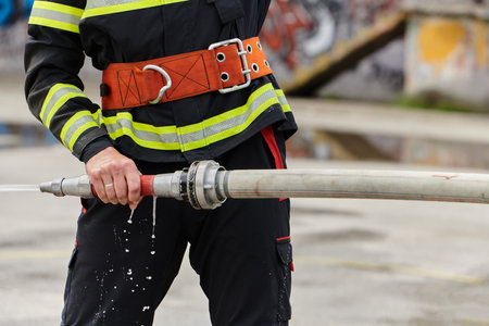 In a dynamic display of synchronized teamwork, firefighters hustle to carry, connect, and deploy firefighting hoses with precision, showcasing their intensive training and readiness for challenging and high-risk situations aheadの写真素材