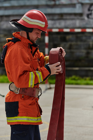 Professional Firefighter Cleaning Up Fire Hose After Extinguishing Blaze