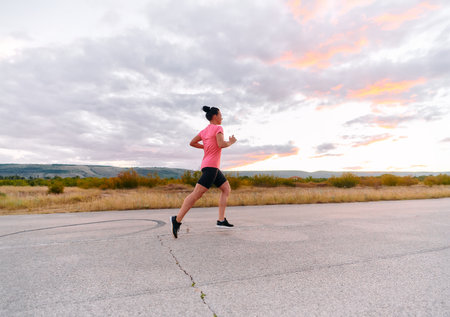 Determined Athlete Running in the Sun amidst Beautiful Natureの写真素材