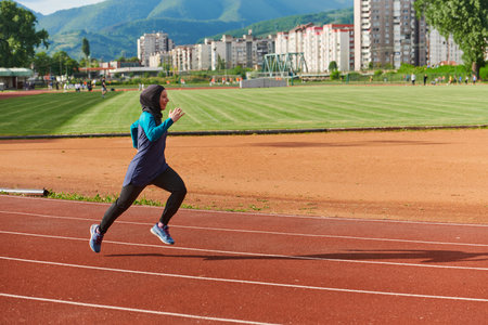 A muslim woman in a burqa sports muslim clothes running on a marathon course and preparing for upcoming competitionsの写真素材