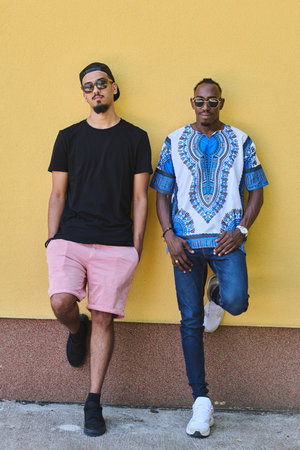 Sudanese Tradition Meets Modern Youth: African American Teen in Vibrant Traditional Attire Against a Yellow Backdropの写真素材