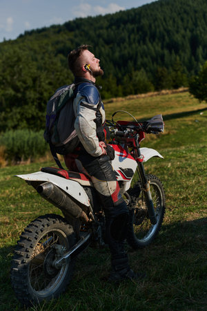 A professional motocross rider, fully geared up with helmet, gloves, and goggles, sits poised on their motorcycle, ready to embark on a thrilling training session through the challenging forest terrainの写真素材