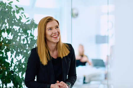 Portrait of a Blonde Businesswoman in a Modern Office with Her Workspace and Colleagues in the...