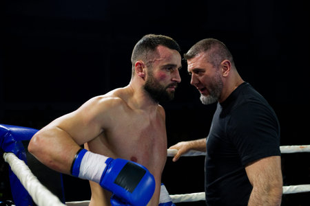 Cornered boxer receives strategic advice from trainer during intense bout.の写真素材