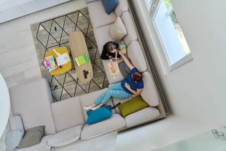 Top View of Mother and Daughter Enjoying a Fun Board Game on the Couch at Home