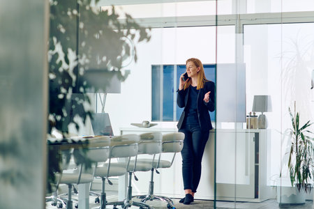 Businesswoman Talking on Smartphone in Modern Office Setting.の写真素材
