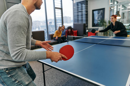 Business colleagues take a break from work to enjoy a game of table tennis, fostering teamwork and camaraderie in the workplaceの写真素材
