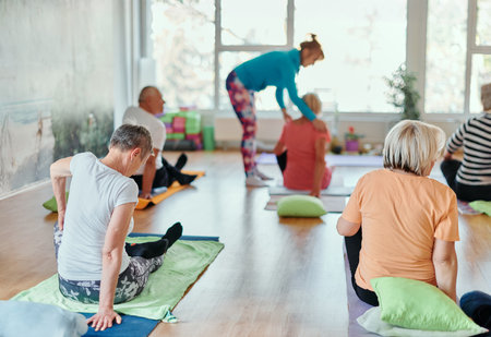 Senior Women Embrace Wellness: Yoga and Stretching in a Sunlit Spaceの写真素材