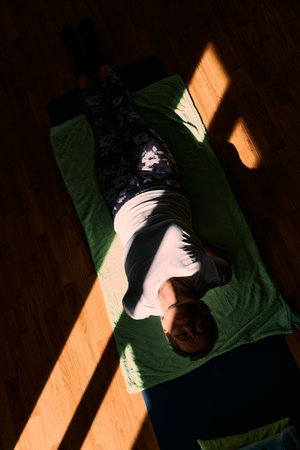 Senior woman practicing stretching and meditation on the floor, focusing on proper alignment and...