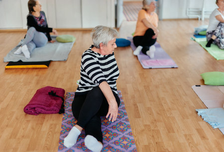 Senior Women Embrace Wellness: Yoga and Stretching in a Sunlit Space