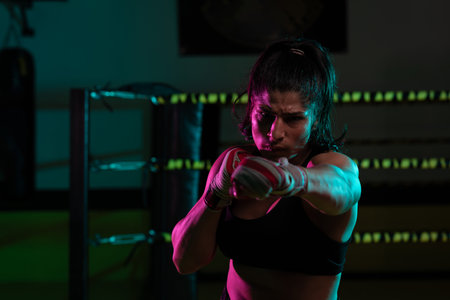 female Latina boxer with her hands bandaged working out at a training session at a gym throwing a punchの写真素材